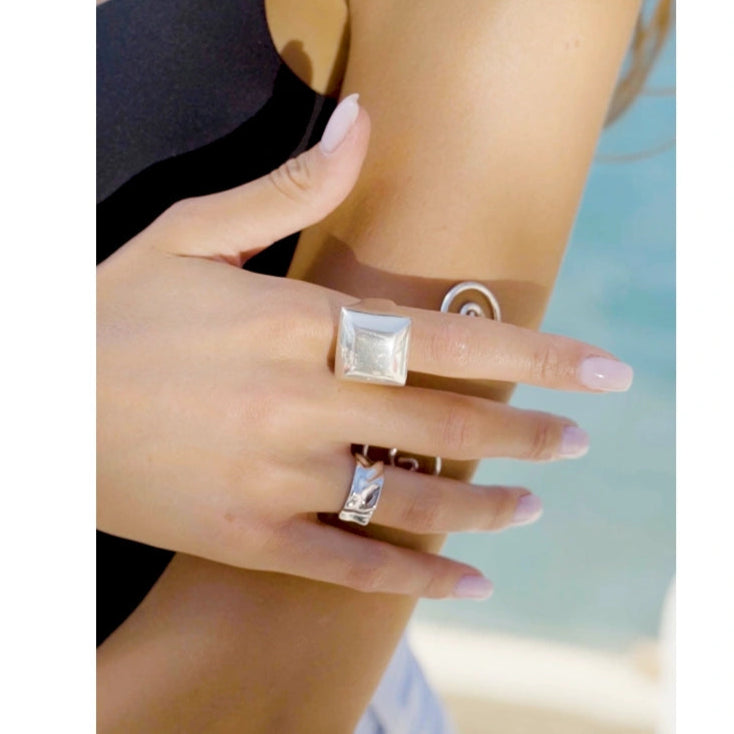 Close-up of a person's hand wearing two rings with a blurred background