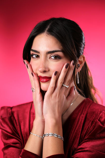 Woman in a red outfit with jewelry against a pink background